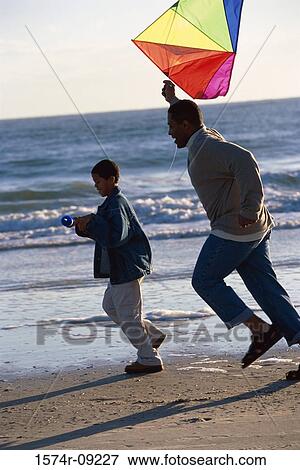 Father and son flying a kite on the beach View Large Photo Image Stock Photo - Father and son flying a kite on the beach. Fotosearch
