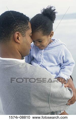 Stock Image - Father carrying his daughter on the beach. Fotosearch