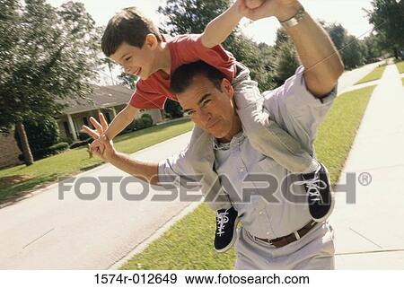 Father carrying his son on his shoulders View Large Photo Image Stock Photo - Father carrying his son on his shoulders. Fotosearch