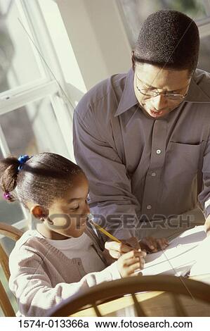 Stock Image - Father helping his daughter with her homework. Fotosearch