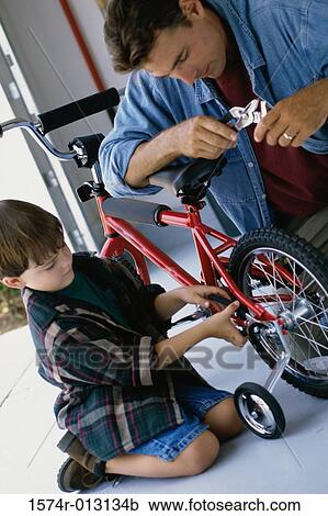 Stock Image - Father repairing a bicycle with his son. Fotosearch