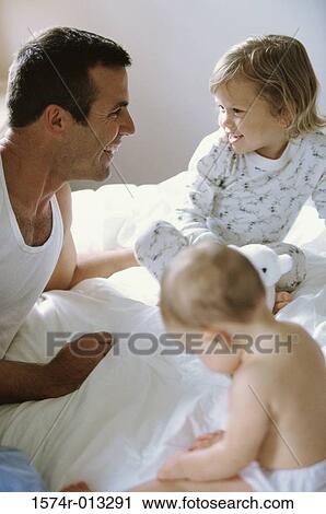 Father sitting with his son and daughter on a bed View Large Photo Image Stock Image - Father sitting with his son and daughter on a bed. Fotosearch