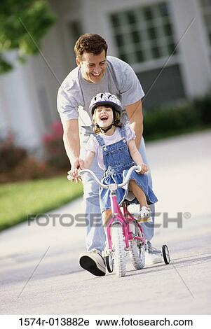 Father teaching his daughter to ride a bicycle View Large Photo Image Stock Image - Father teaching his daughter to ride a bicycle. Fotosearch
