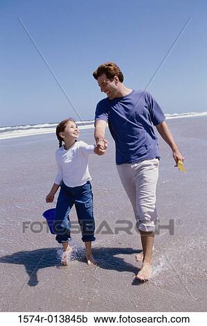 Father walking with his daughter on the beach View Large Photo Image Stock Image - Father walking with his daughter on the beach. Fotosearch