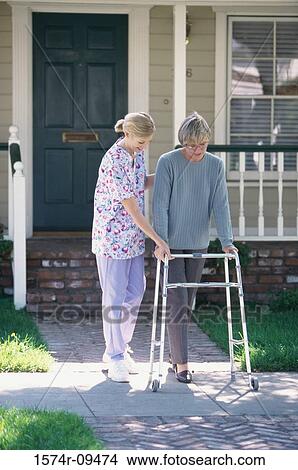 Female nurse helping a female patient walk with a walker View Large Photo Image Picture - Female nurse helping a female patient walk with a walker. Fotosearch