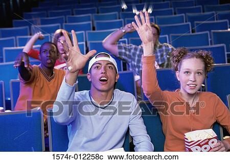 Five teenagers sitting in a movie theater throwing popcorns View Large Photo Image Stock Image - Five teenagers sitting in a movie theater throwing popcorns. Fotosearch