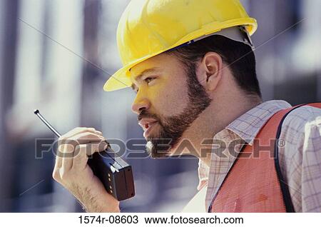 Stock Image - Foreman talking on a walkie-talkie. Fotosearch