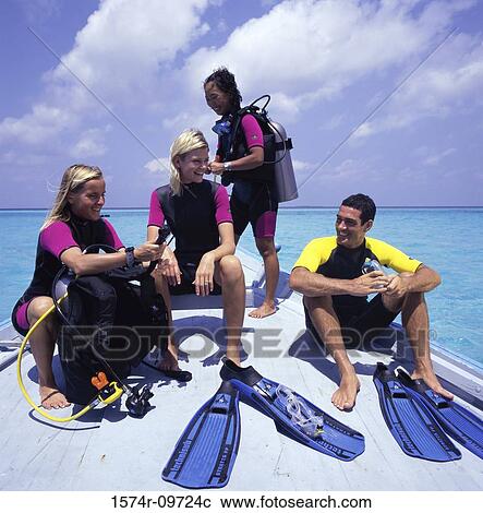 Four people in scuba gear sitting on the bow of a boat View Large Photo Image Stock Image - Four people in scuba gear sitting on the bow of a boat. Fotosearch