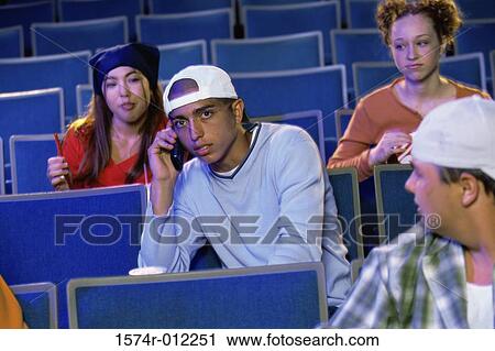 Stock Image - Four teenagers sitting in a movie theater. Fotosearch