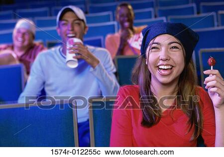 Stock Image - Four teenagers sitting in a movie theater. Fotosearch