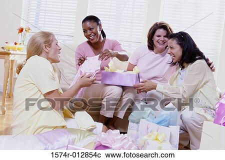 Stock Image - Four women opening gifts at a baby shower. Fotosearch