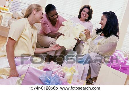 Stock Image - Four women opening gifts at a baby shower. Fotosearch