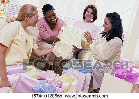 Stock Image - Four women opening gifts at a baby shower. Fotosearch