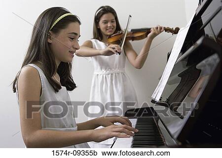 Stock Image - Girl playing the piano and another playing the violin. Fotosearch