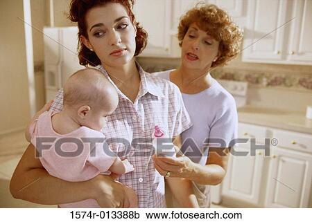 Grandmother giving a milk bottle to her granddaughter being held by her mother View Large Photo Image Stock Image - Grandmother giving a milk bottle to her granddaughter being held by her mother. Fotosearch