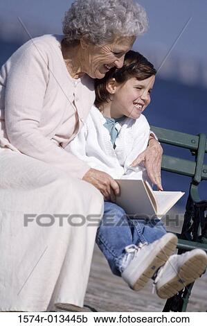 Stock Image - Grandmother sitting on a bench with her granddaughter. Fotosearch