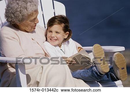 Stock Image - Grandmother sitting with her granddaughter and smiling. Fotosearch