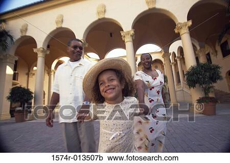 Stock Image - Grandparents walking with their granddaughter. Fotosearch