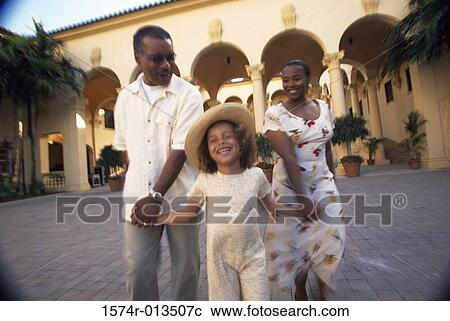 Stock Image - Grandparents walking with their granddaughter. Fotosearch