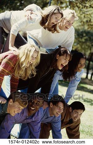 Stock Image - Group of people making a human pyramid in a garden. Fotosearch