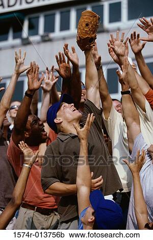 Stock Image - Group of people reaching up for a baseball. Fotosearch