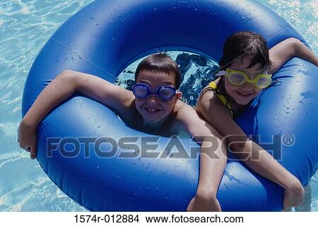 High angle view of a boy and a girl swimming with an inflatable ring in a swimming pool View Large Photo Image Picture - High angle view of a boy and a girl swimming with an inflatable ring in a swimming pool. Fotosearch