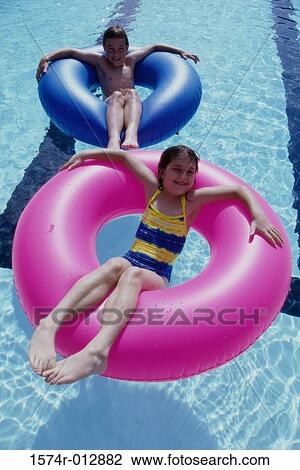 High angle view of a boy and a girl lying on inflatable rings in a swimming pool View Large Photo Image Stock Image - High angle view of a boy and a girl lying on inflatable rings in a swimming pool. Fotosearch