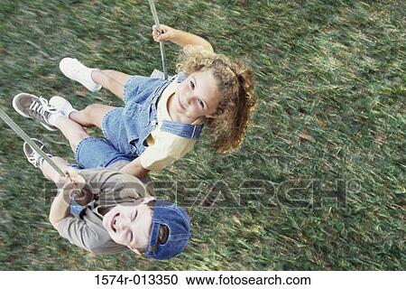 High angle view of a boy and girl swinging on a swing View Large Photo Image Stock Image - High angle view of a boy and girl swinging on a swing. Fotosearch