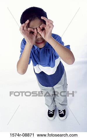 Stock Image - High angle view of a boy holding his hands up to his eyes. Fotosearch