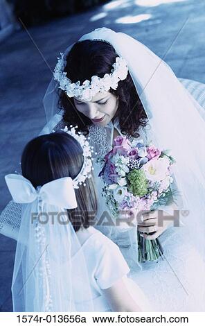 Stock Image - High angle view of a bride sitting with a flower girl. Fotosearch