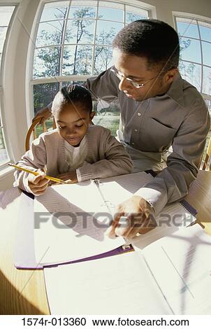 Stock Image - High angle view of a father helping his daughter with her homework. Fotosearch