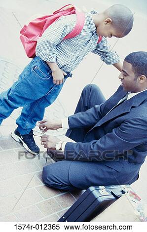Stock Photography - High angle view of a father tying his son's shoelaces. Fotosearch