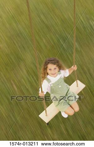 Stock Image - High angle view of a girl swinging on a swing. Fotosearch