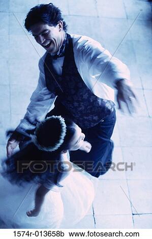 Stock Image - High angle view of a groom dancing with a flower girl. Fotosearch