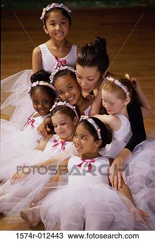 Stock Image - High angle view of a group of ballet dancers sitting with their teacher. Fotosearch