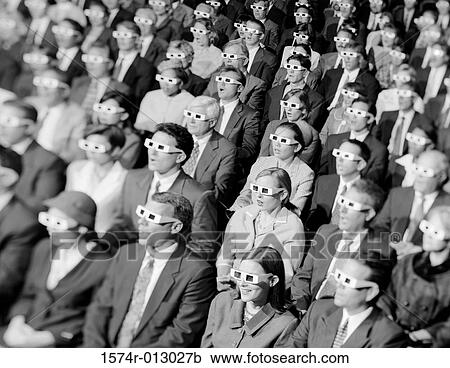 Stock Image - High angle view of a group of spectators sitting in a movie theater wearing 3-D glasses. Fotosearch