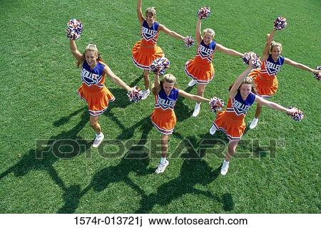 Stock Image - High angle view of a group of cheerleaders cheering in a field. Fotosearch
