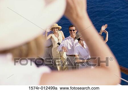 Stock Image - High angle view of a mid adult man and two mid adult women standing on the deck of a cruise ship. Fotosearch