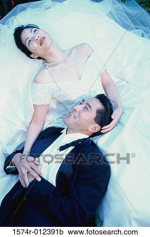 Stock Image - High angle view of a newlywed couple lying down. Fotosearch