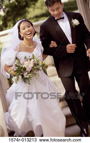 Stock Image - High angle view of a newlywed couple running. Fotosearch