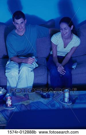 High angle view of a young couple sitting on a couch watching television View Large Photo Image Stock Image - High angle view of a young couple sitting on a couch watching television. Fotosearch