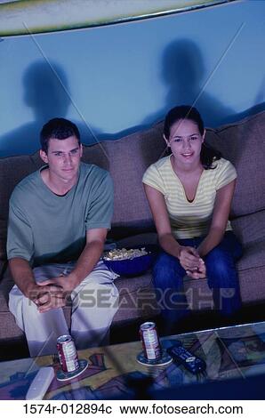 High angle view of a young couple sitting on a couch watching television View Large Photo Image Stock Image - High angle view of a young couple sitting on a couch watching television. Fotosearch