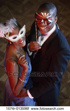 Stock Image - High angle view of a young couple wearing masks. Fotosearch