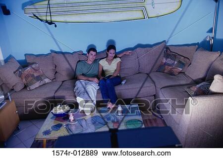 High angle view of a young couple sitting on a couch watching television View Large Photo Image Stock Photo - High angle view of a young couple sitting on a couch watching television. Fotosearch