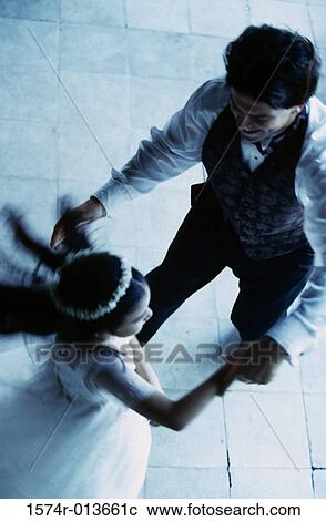 Stock Image - High angle view of a young man dancing with a flower girl. Fotosearch