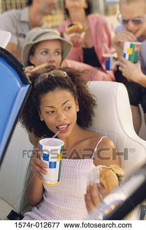 High angle view of a young woman eating food with her friends in a car View Large Photo Image Stock Photo - High angle view of a young woman eating food with her friends in a car. Fotosearch