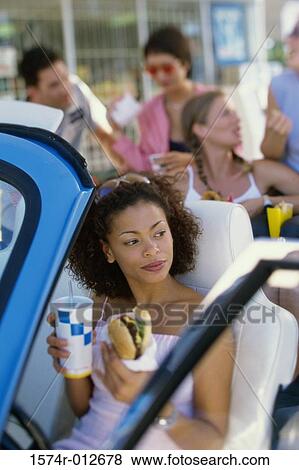 High angle view of a young woman eating food with her friends in a car View Large Photo Image Stock Photo - High angle view of a young woman eating food with her friends in a car. Fotosearch