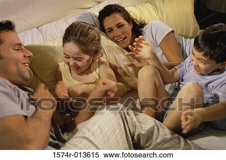 Stock Photography - High angle view of parents and their two children playing in bed. Fotosearch