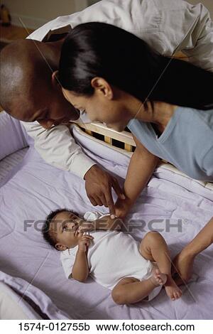 Stock Image - High angle view of parents looking at their son in a crib. Fotosearch