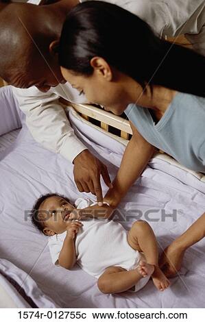 Stock Image - High angle view of parents looking at their son in a crib. Fotosearch